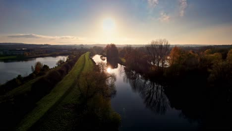 Vista-Aérea-De-Drones-Sobre-El-Río-Y-Los-árboles-De-Otoño-Del-Bosque-Durante-La-Puesta-De-Sol