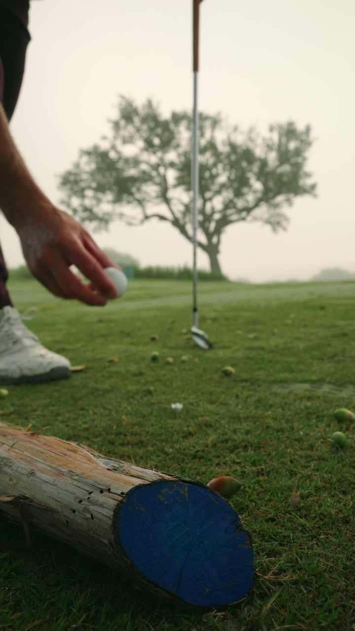 Vertical ground-level view of golfer’s hand placing ball on tee. Highlights precise setup, stance preparation, and attention to detail before tee shot