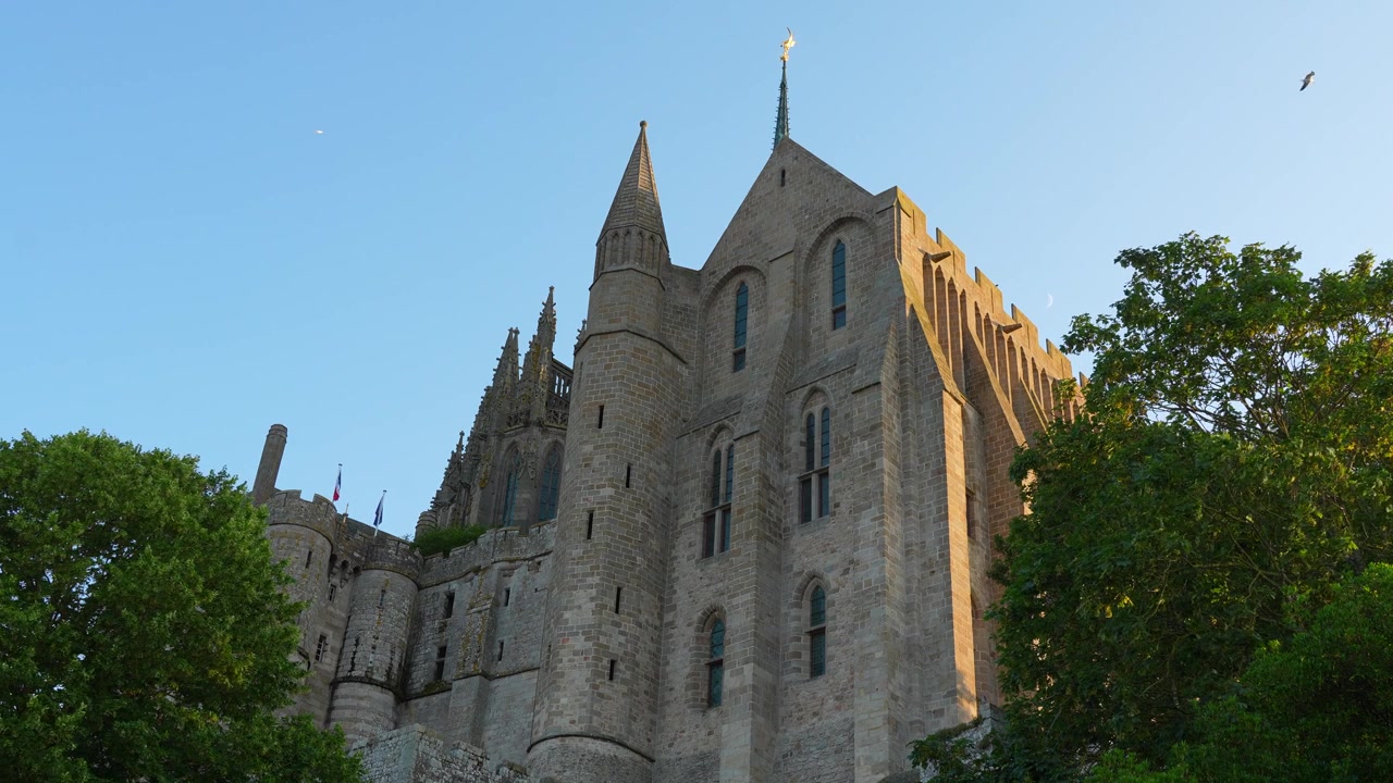 Vista al rallentatore dell'Abbazia di Mont Saint-Michel illuminata dalla calda luce della sera, che mostra l'architettura gotica in Normandia, Francia.