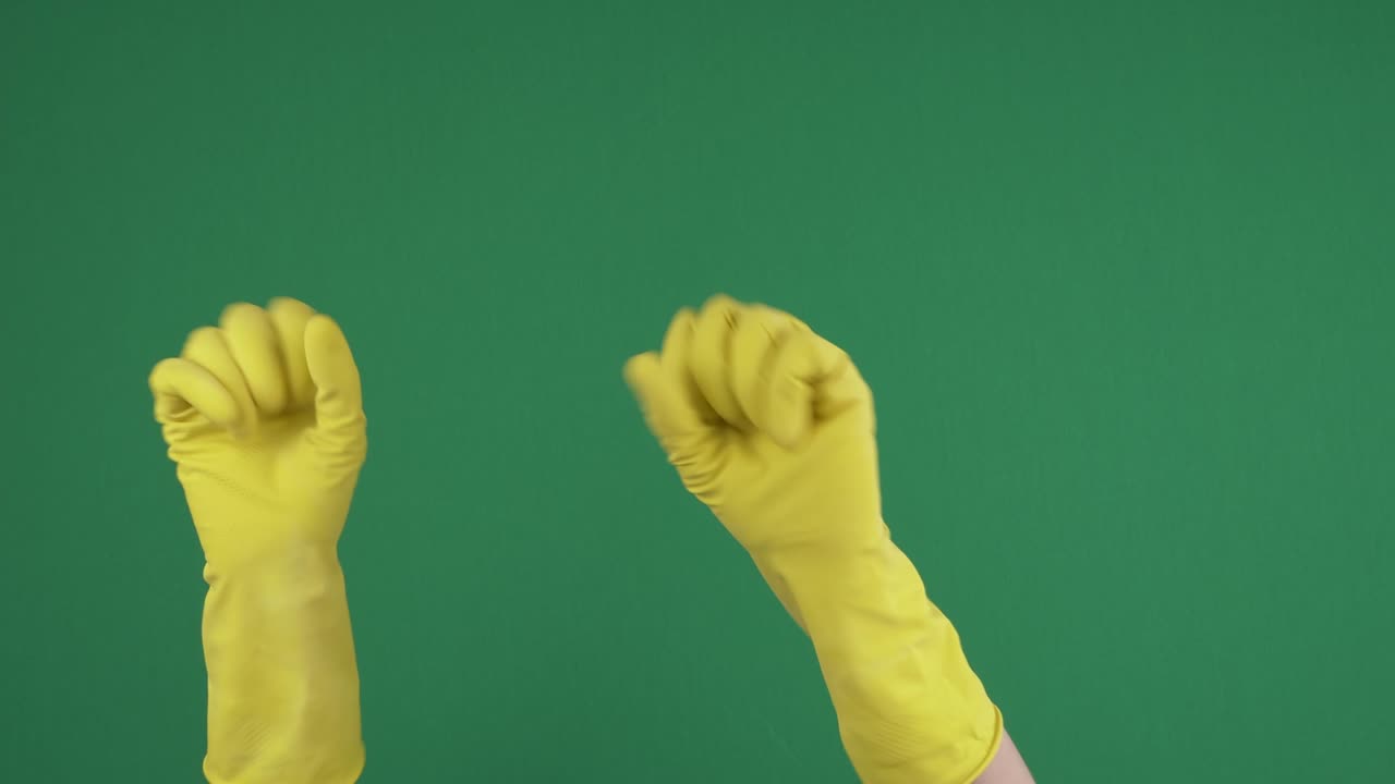 Female hands with yellow protective rubber gloves dancing. Woman hands show ok sign, joyfully clench and unclench their fingers over green chromakey background. 4k video