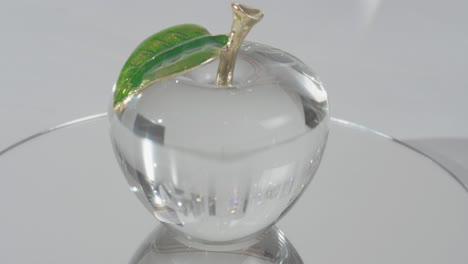 crystal glass apple on top of a mirror shinning light through