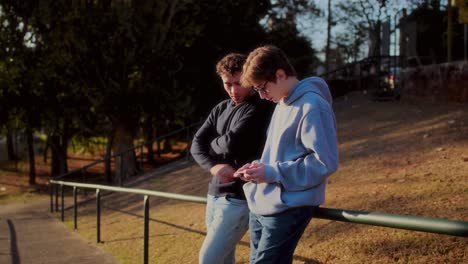two young men engaged with smartphones outdoors