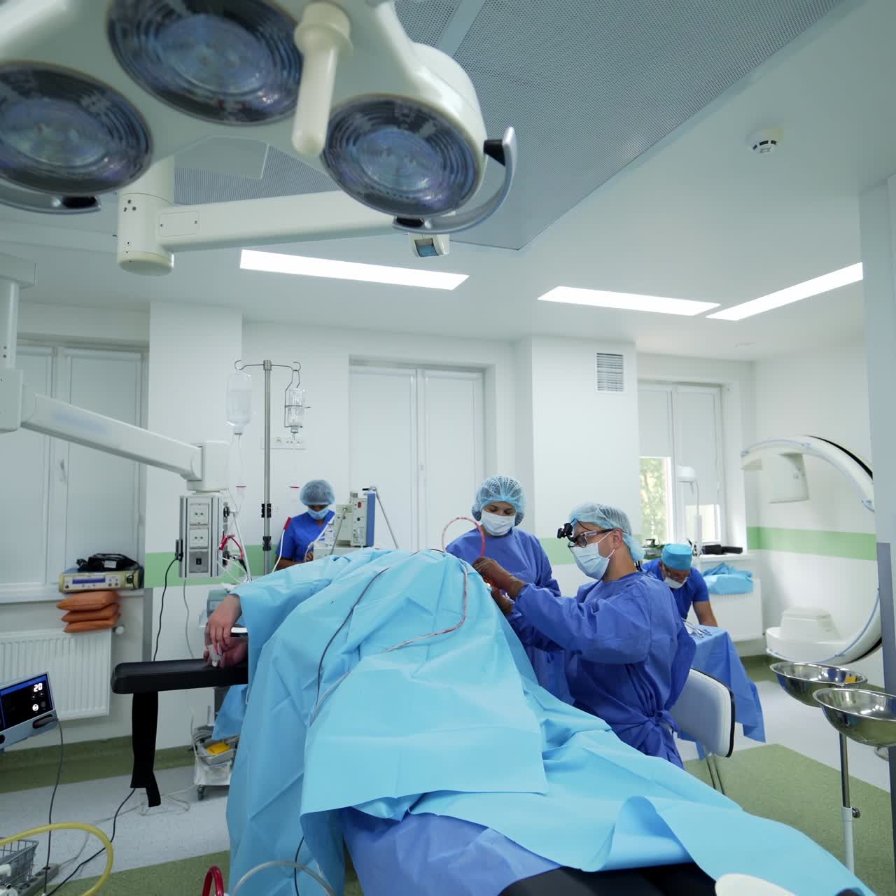Modern operating theater. Medical staff in blue uniform perform an operation on a patient on the background of surgical equipment. Unconsciousness patient on surgical table