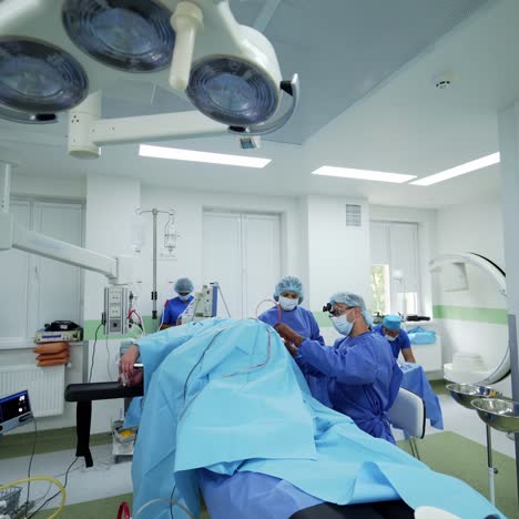 modern operating theater. medical staff in blue uniform perform an operation on a patient on the background of surgical equipment. unconsciousness patient on surgical table