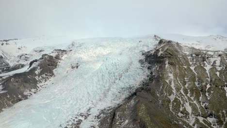 icy glacier summit, snow-cap mountain peak, clear sky, aerial approach