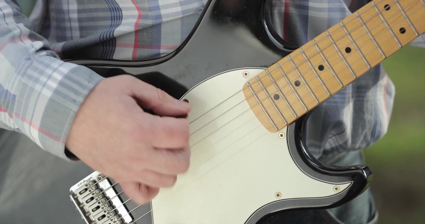 Primo piano della mano di un uomo che suona una chitarra elettrica, 4K