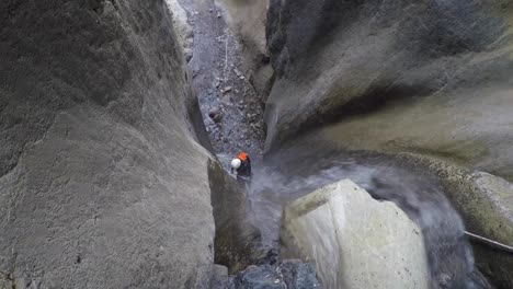 woman canyoneer rappels waterfall into limestone canyon far below