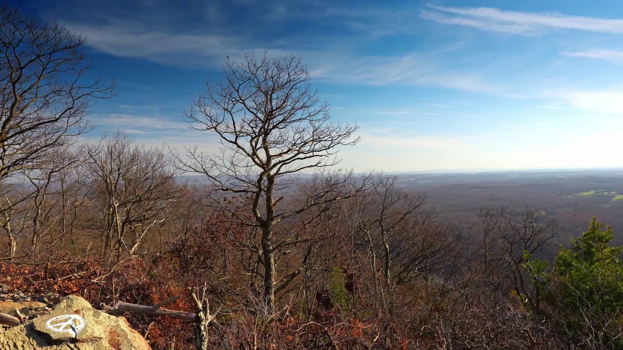 Segnavia bianco su roccia sulla cima del Monte Tammany. Alberi spogli e primo piano roccioso con segnavia bianco che si affaccia su una vasta valle boscosa e sull'orizzonte.
