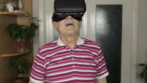 senior grandfather man in virtual headset glasses watching 3d video in 360 vr helmet at home