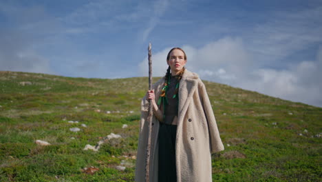 hiking woman standing highland with stick. travel girl warming on sun