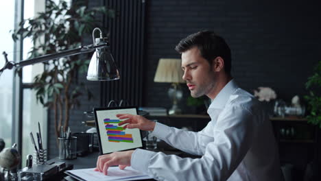 hombre de negocios analizando estadísticas financieras en documentos con gráficos en una computadora portátil