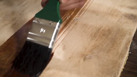 close shot of a paint brush putting wood oil on a wood