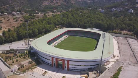 aerial view of a modern football stadium in a city surrounded by mountains