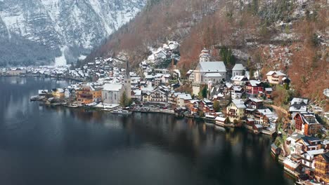 aerial orbiting shot of hallstatt lakeside town covered in snow, austrian landscape