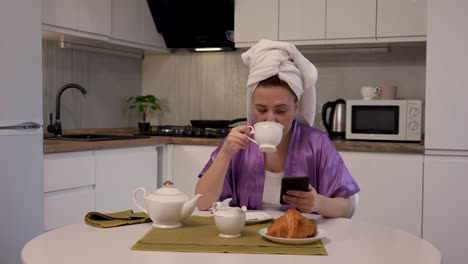 woman having breakfast and using phone in kitchen