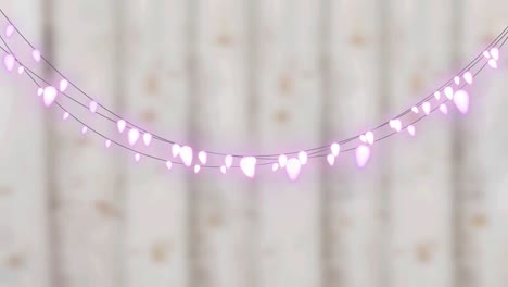 Digital-animation-of-pink-decorative-fairy-lights-hanging-against-wooden-background