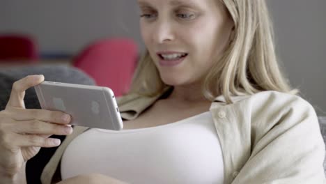 serious pregnant woman having video call via smartphone