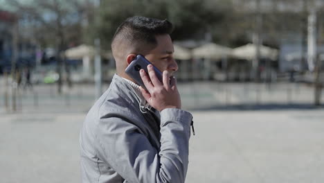 hombre de oriente medio alegre hablando en el teléfono inteligente al aire libre