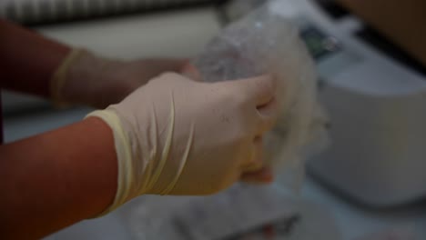 gloved hands of a hygienist unwrapping a dental model from plastic film in a dental clinic. close up