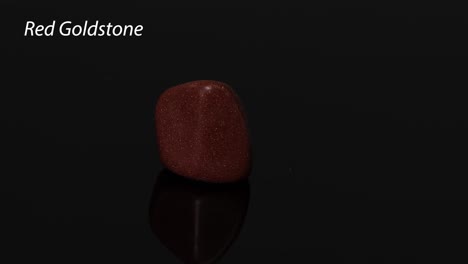 a red goldstone rotates on a reflective surface.