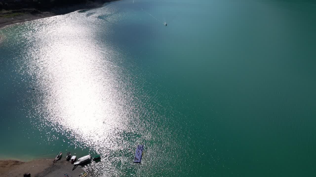 Flying over Pluzine beach resort revealing the turquiose lake Pivsko near Pluzine surrounded by green forrests and mountains in Montenegro druing august summertime