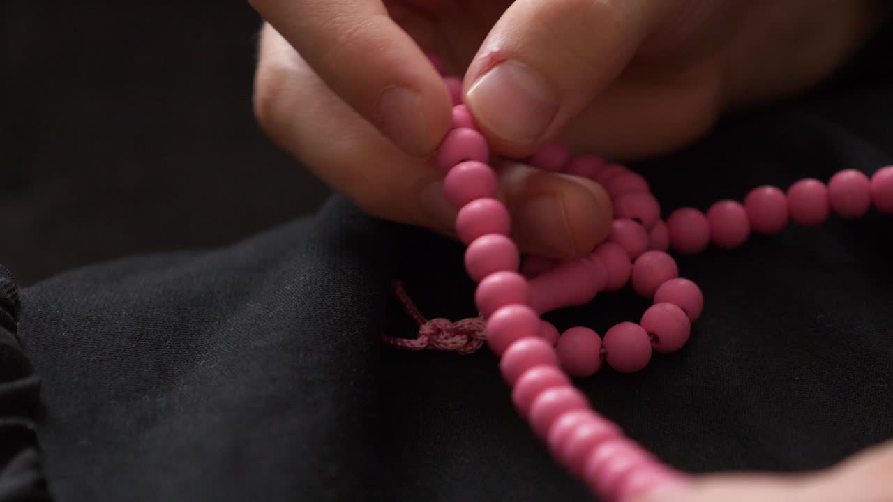 fotografía de cerca de una cuentas de oración y una persona que las usa para el dhikr