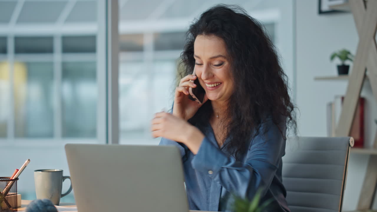 Cheerful woman talking phone in modern office feeling happy. Closeup boss call