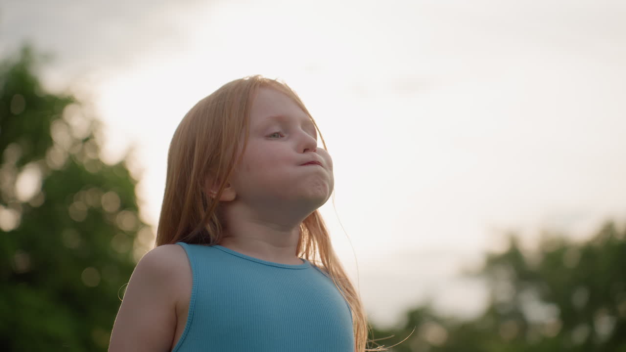 close up of girl closing eyes tight and puckering mouth while mom sprays insect mist on her in sunny park, casual clothing, warm light showing playful protective moment during summer family time