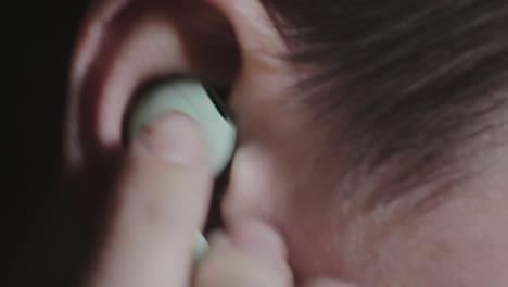 Putting-And-Removing-A-Light-Green-Earphone-In-The-Ear---Closeup-Shot