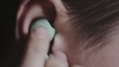 putting and removing a light green earphone in the ear - closeup shot