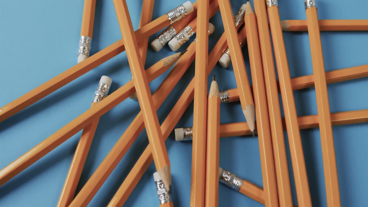 vista aérea de lápices dispersos con fondo azul, en cámara lenta