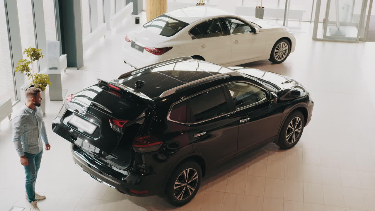 hombre mirando el maletero del coche en la sala de exposiciones