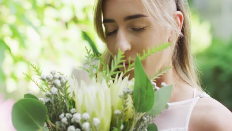 happy caucasian woman holding bunch of flowers in garden on sunny day