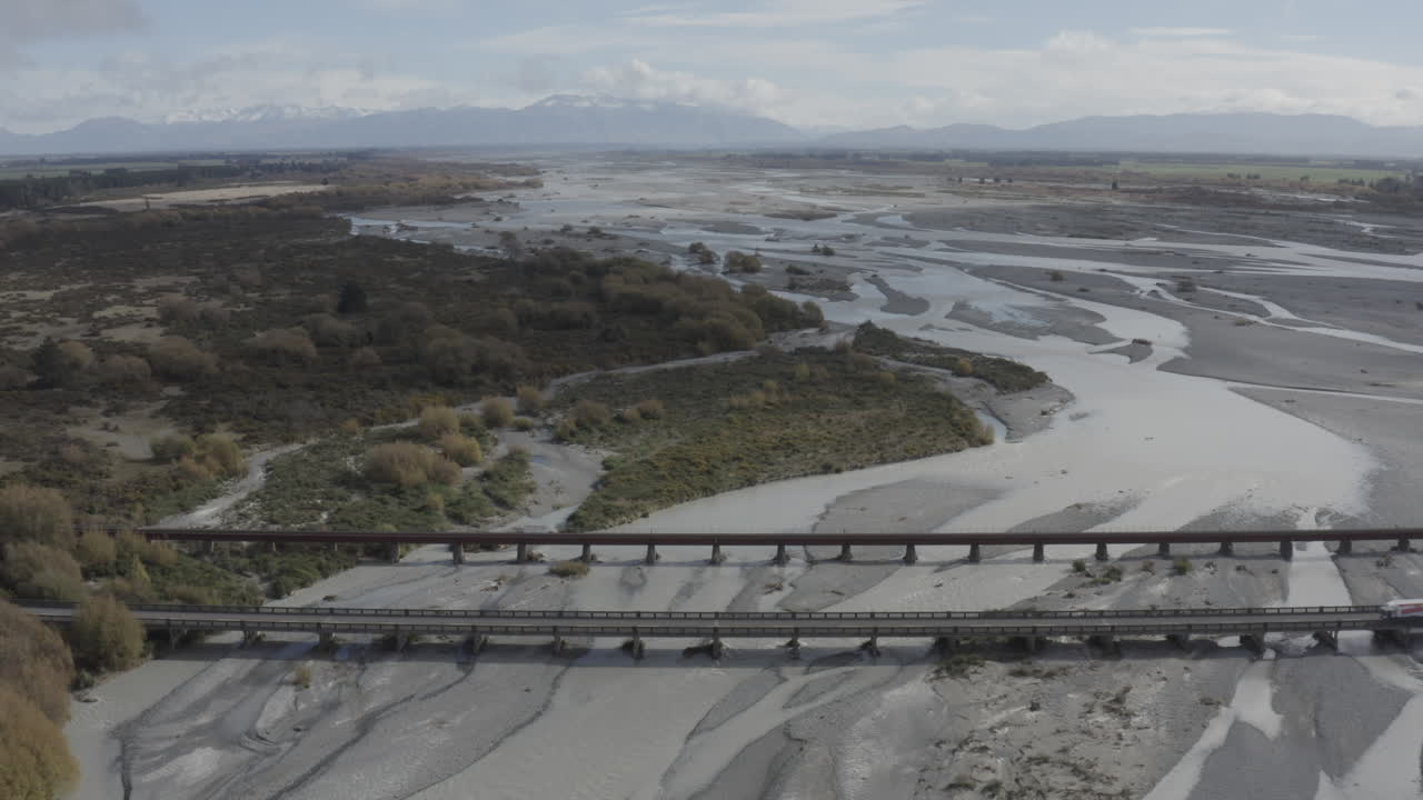fotografía aérea del puente rakaia con montañas en el horizonte, en la isla sur de nueva zelanda