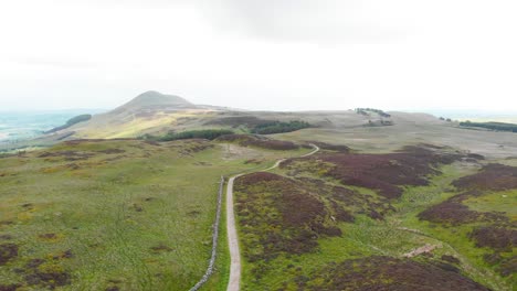 gravel road along rock wall in lomond hills highland in scotland, drone