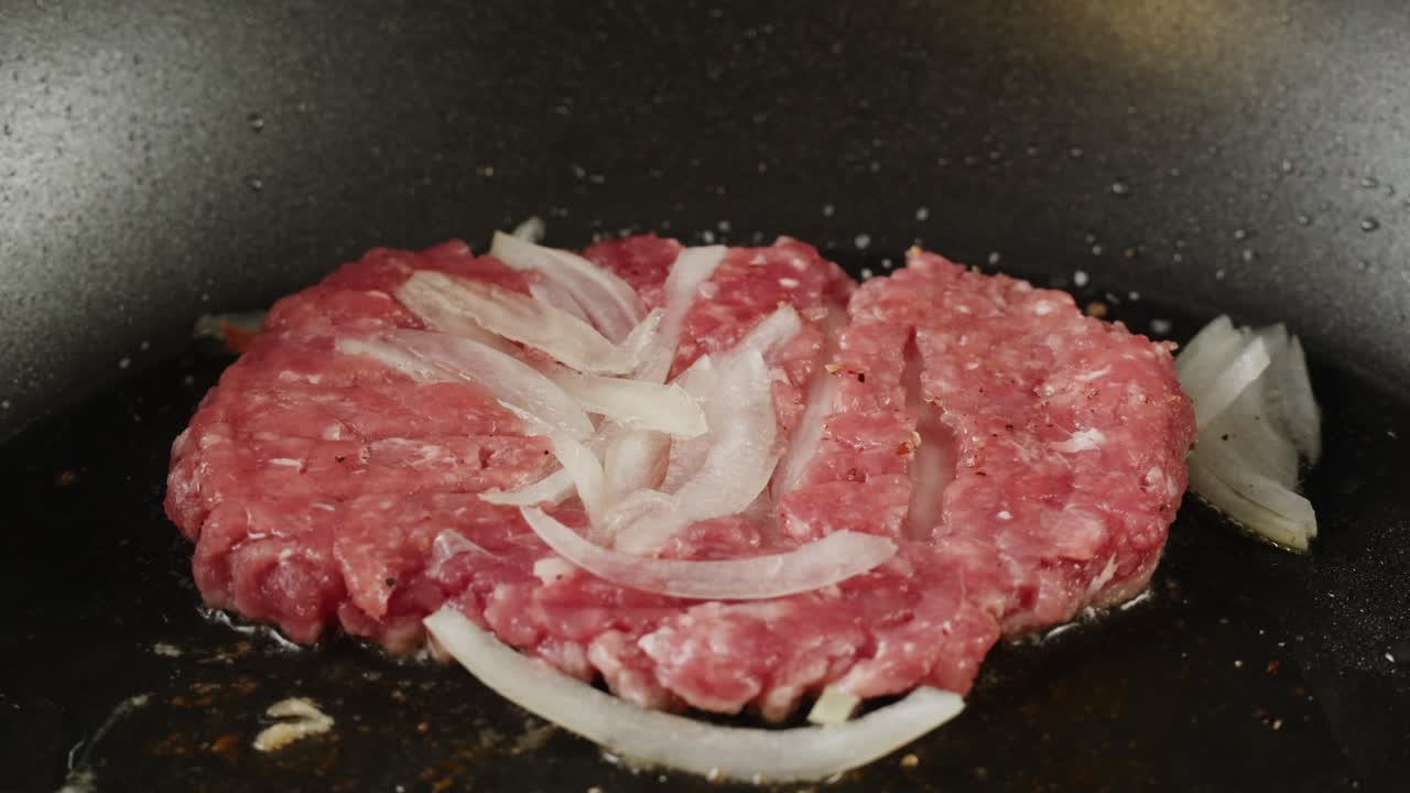 Cooking a Raw Hamburger Patty with Onions in a Pan