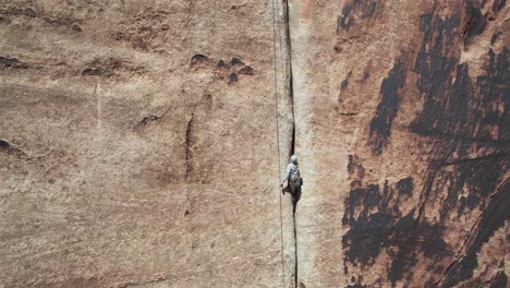 Luftaufnahme-Eines-Kletterers-Auf-Einem-Massiven-Vertikalen-Felsen,-Der-Versucht,-Nach-Oben-Zu-Klettern,-Drohnenaufnahme