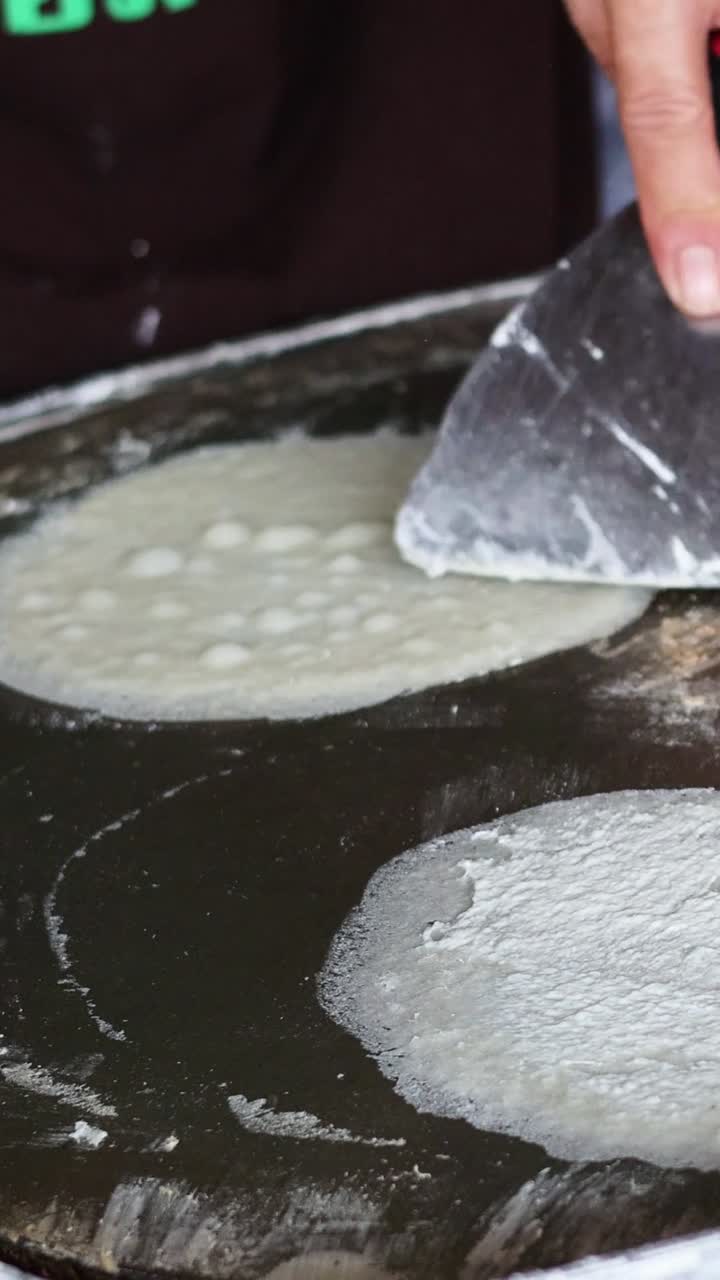Person skillfully cooking flatbreads on a large griddle