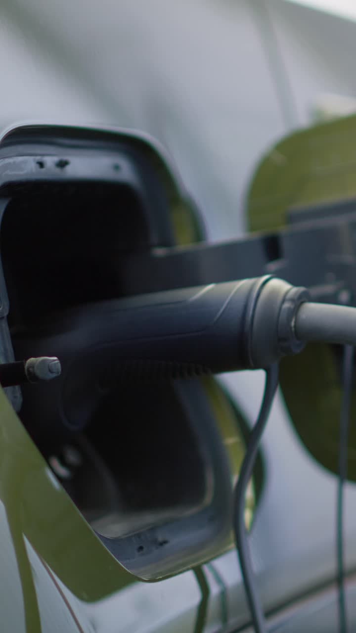 Vertical video Close up shot of EV eco friendly car being charged while parked