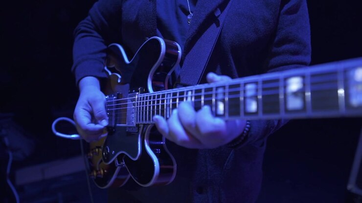 Primo piano di una persona che suona la chitarra a un concerto