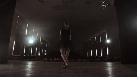 slow motion: the prima ballerina in a black dress performs rotations and graceful dance moves. the camera moves on gimbal