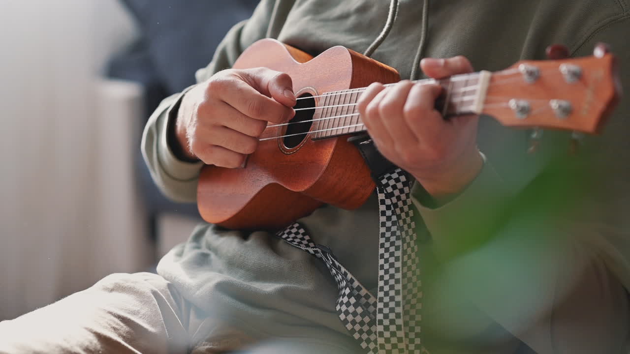 우쿨렐레를 연주하는 알아볼 수 없는 남자의 손 1