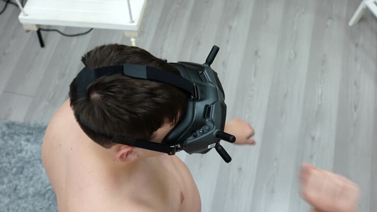 Giovane che gioca a un videogioco d'azione indossando un visore VR, ripresa dall'alto