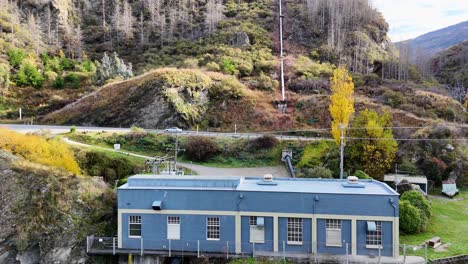 Drone footage captures a hydroelectric power station in Queenstown, New Zealand, surrounded by autumn foliage and rugged landscape