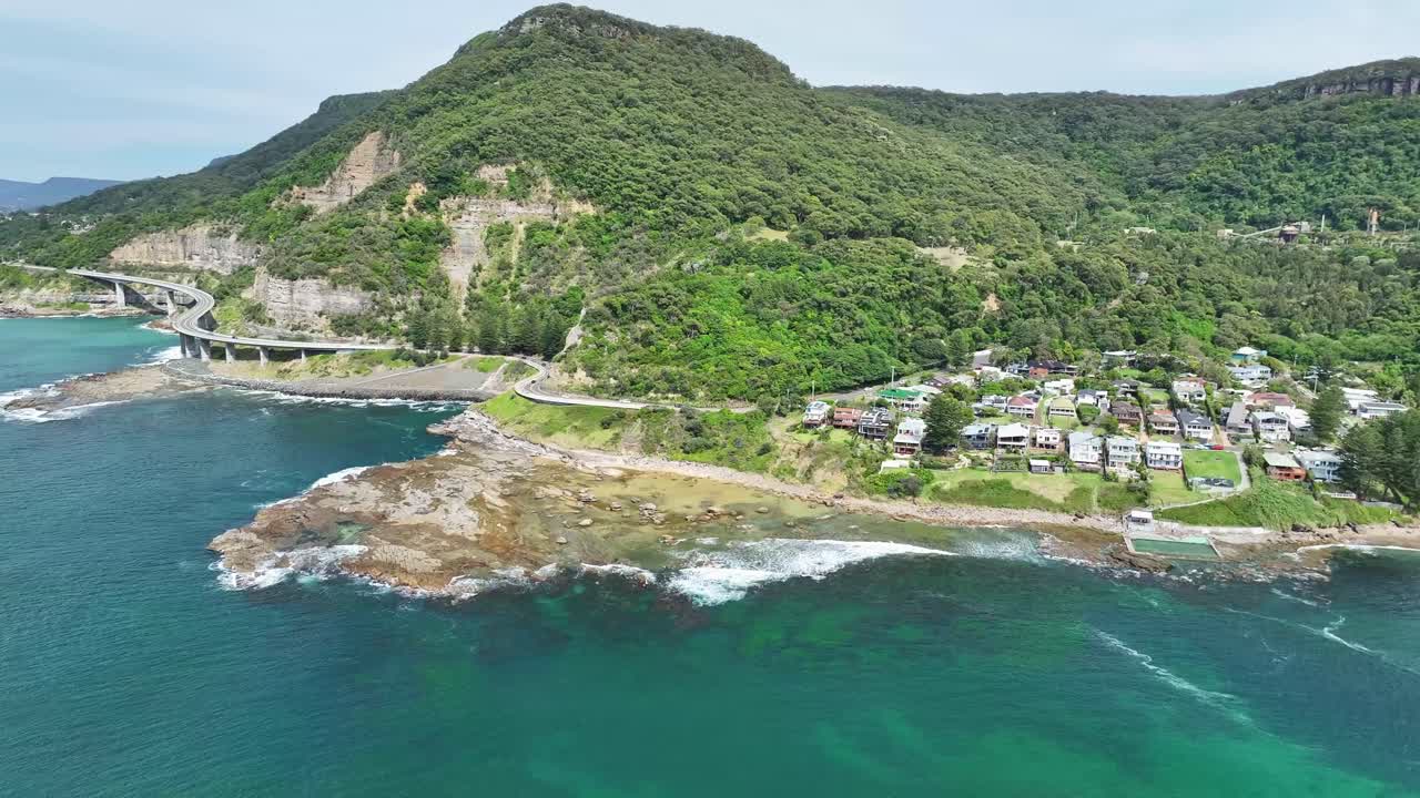 The rocky shore and pools of Coalcliff Beach with the Sea Cliff Bridge and winding road beyond