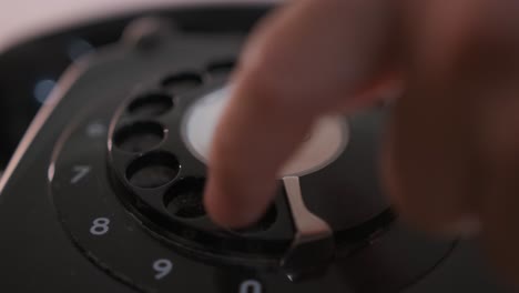 close-up of the dialing wheel of a rotary phone as a person dials a number