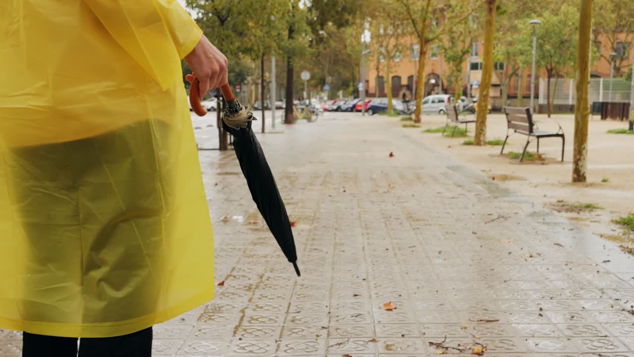 Uomo d'affari e turista con ombrello e impermeabile su una strada cittadina europea piovosa, con le luci che si riflettono, che cammina a Barcellona o Amsterdam sotto la pioggia