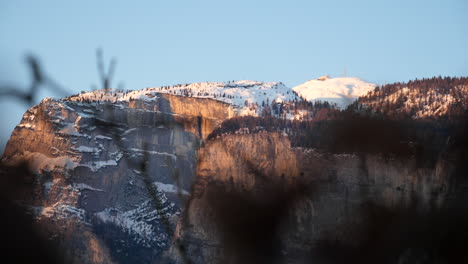 Sunny-mountain-tops-views-through-blurred-foreground-of-branches-in-northern-Trentino-region-of-Italy