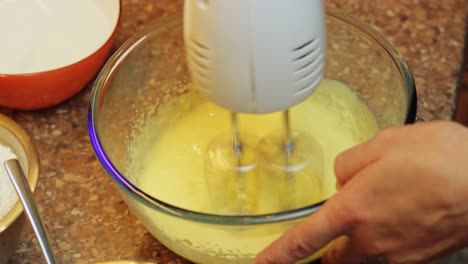 batir la mezcla de masa de pastel de huevo con una batidora de mano
