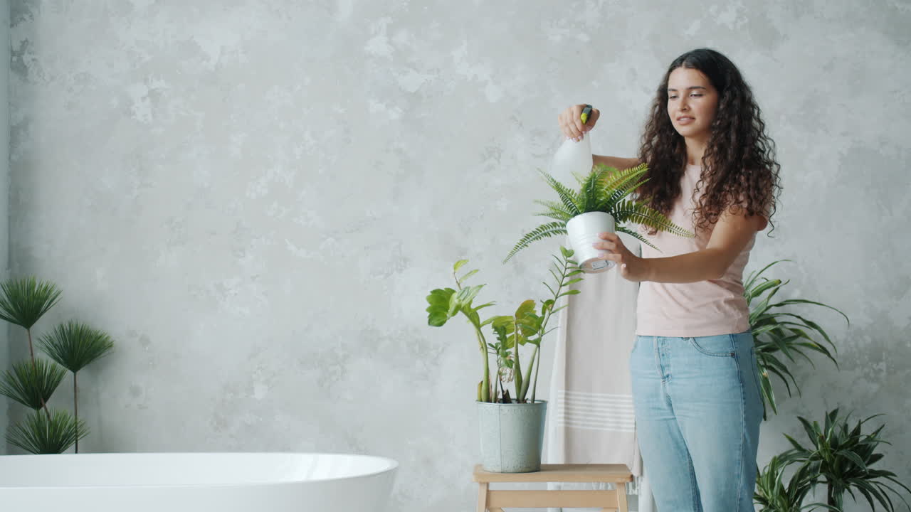 Woman Watering Houseplants in a Bathroom